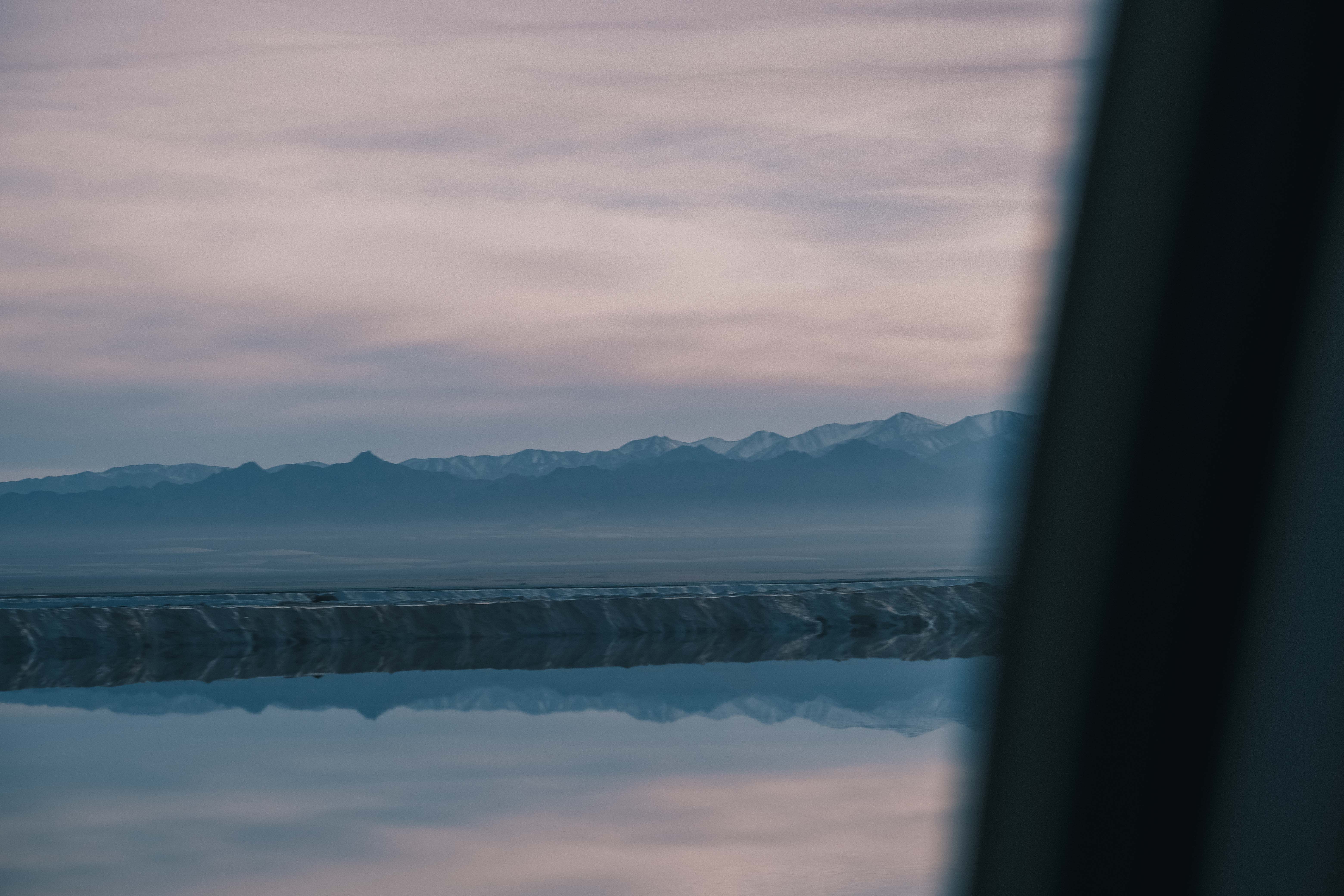 A salt lake and mountains seen past a dark foreground
