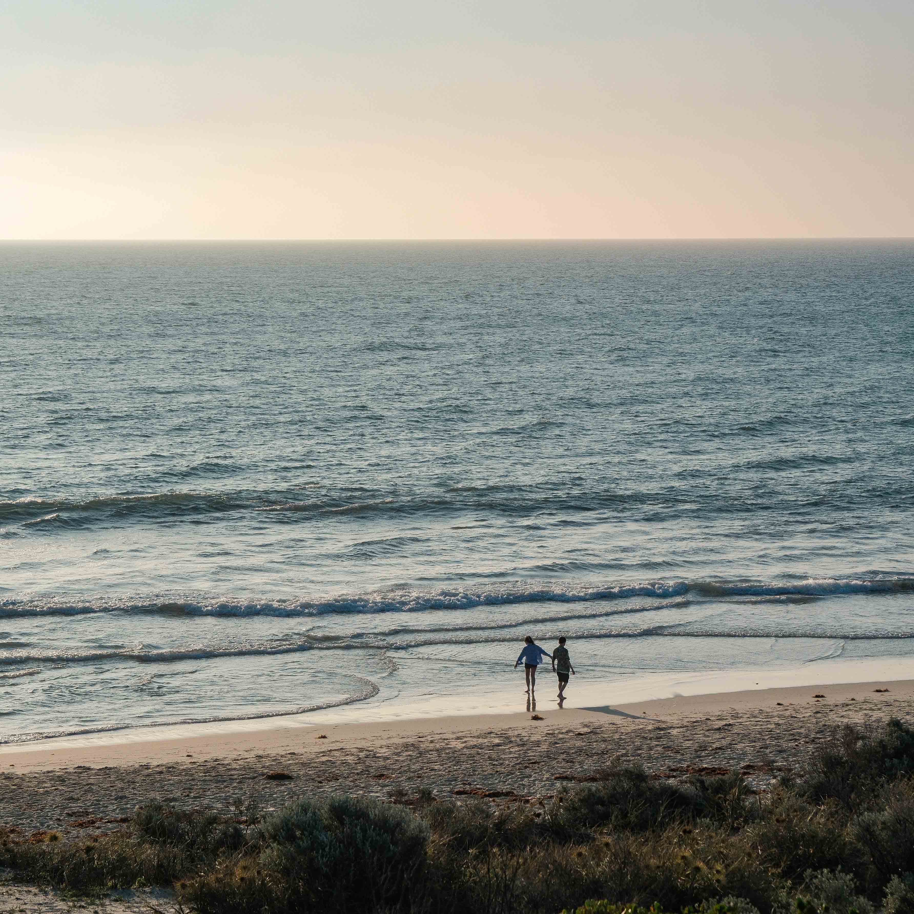 Two people walking together at the edge of the sea
