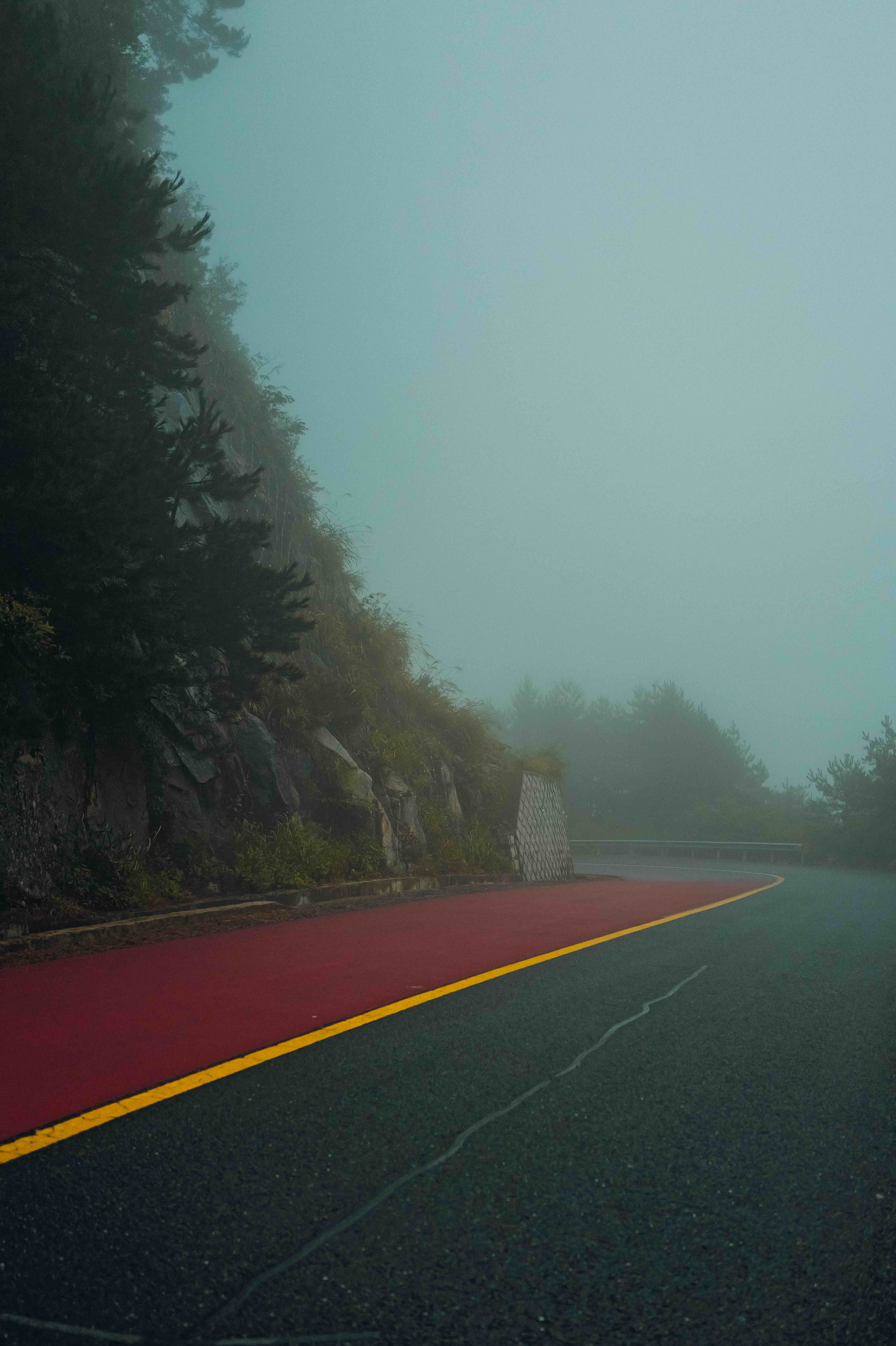 A red and green mountain road in the mist